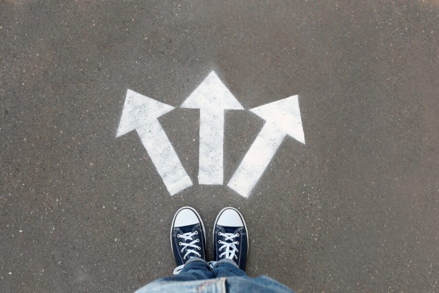 Woman standing near arrows on asphalt, top view. Choice concept